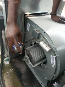 A Facilityfix technicians' HVAC contractor performing cleaning service on a blower motor in Port Harcourt, NG.