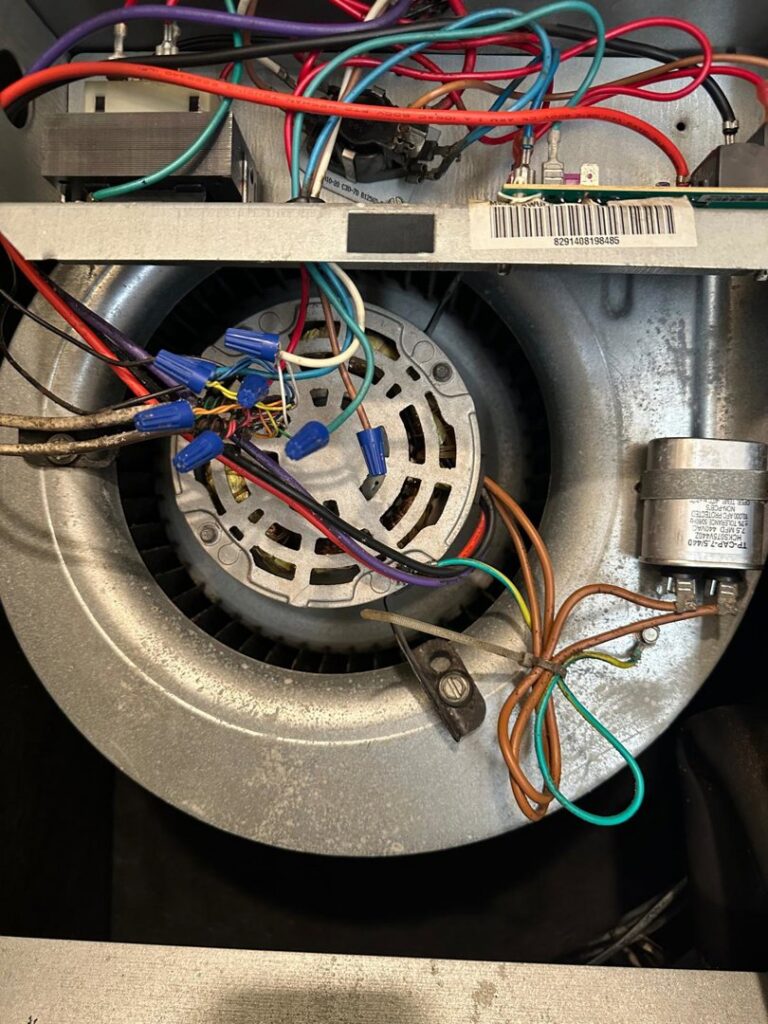 A close-up view of the blower motor and intricate wiring inside an HVAC unit, serviced by Air Casablanca Heating & Cooling in Myrtle Beach, SC.
