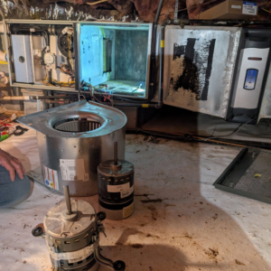 New and old HVAC blower motors and components on the floor during a repair by Speedy Nelson HVAC Repair in Durham, NC.