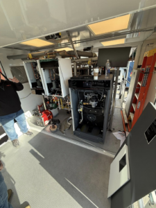An HVAC technician working on a boiler or furnace installation inside a mobile workshop for Graves Heating and Cooling in Saint Paul, MN.