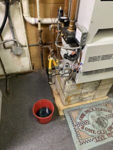 An HVAC boiler or furnace unit with gas lines and electrical connections, undergoing repair by Coe Heating & Air Conditioning in Fort Wayne, IN.