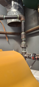 Close-up of boiler piping connections and valves, part of an HVAC system by J Hannah Mechanical Inc in Saco, ME.