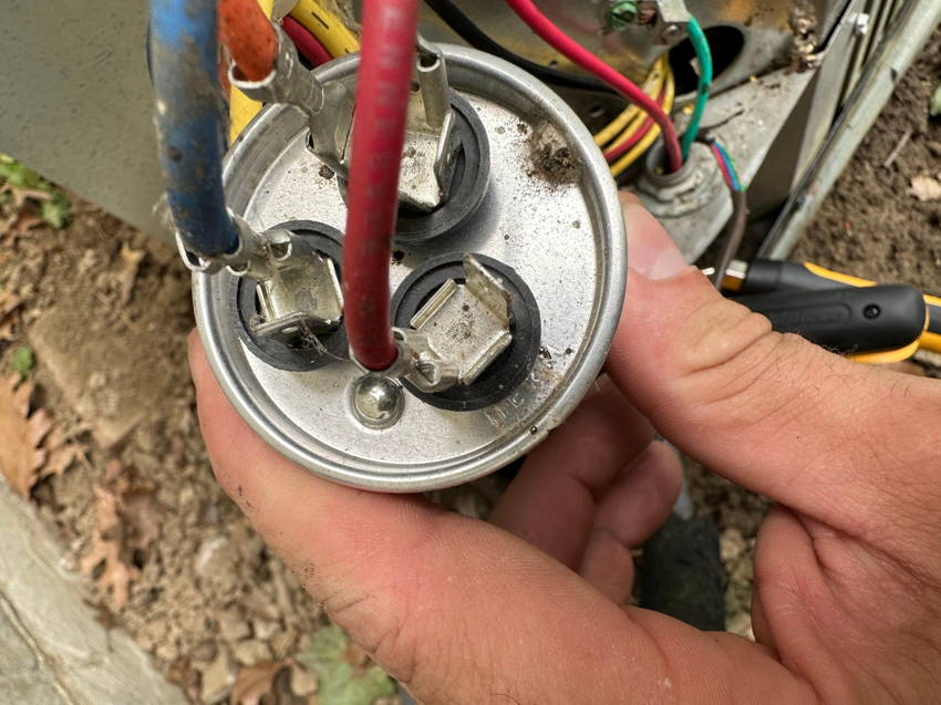 A technician holding an HVAC capacitor during a repair service by Cardinal Repairs in Canton, OH