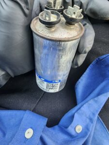 A technician holding an HVAC capacitor during a replacement service by Comfort Zone Mechanical in Antioch, TN.