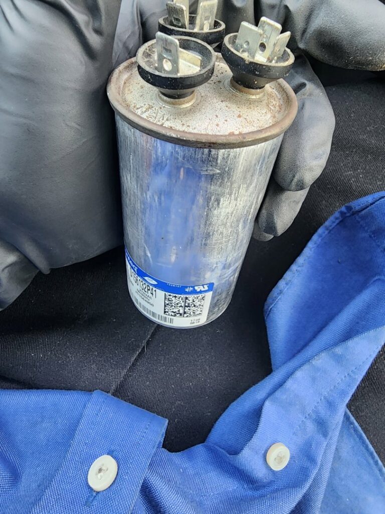 A technician holding an HVAC capacitor during a replacement service by Comfort Zone Mechanical in Antioch, TN.