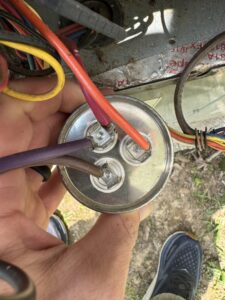 A technician holding an HVAC capacitor during a repair or replacement service by Southern Climate Pros in Jasper, AL.