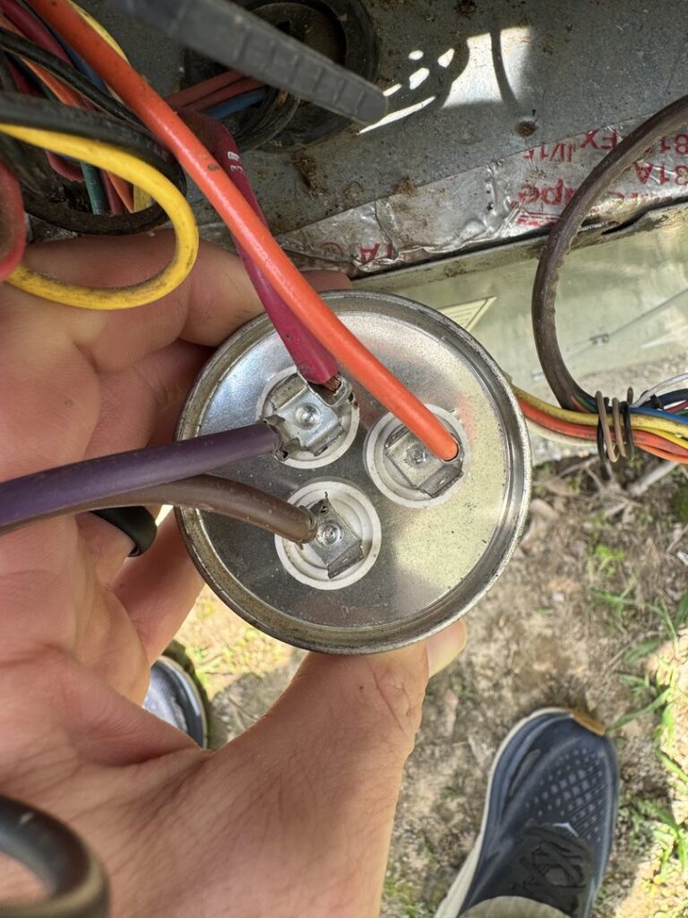 A technician holding an HVAC capacitor during a repair or replacement service by Southern Climate Pros in Jasper, AL.