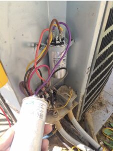An HVAC technician replacing a capacitor in an outdoor air conditioning unit for a client of Triune Air in Smithville, TN.