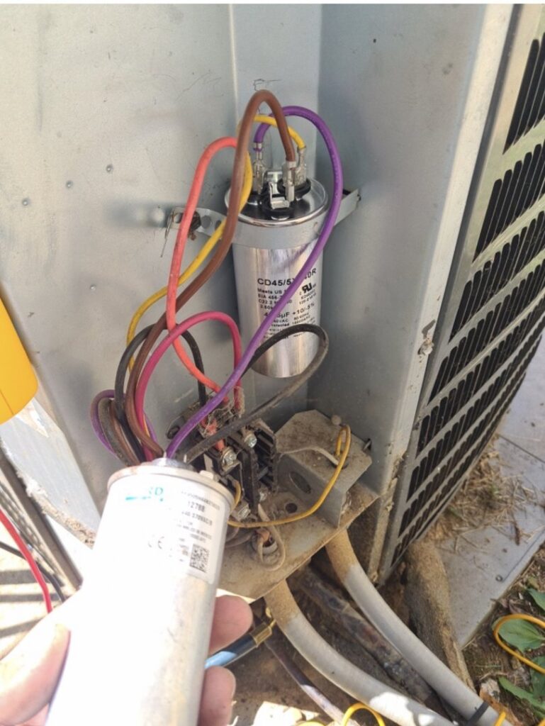 An HVAC technician replacing a capacitor in an outdoor air conditioning unit for a client of Triune Air in Smithville, TN.