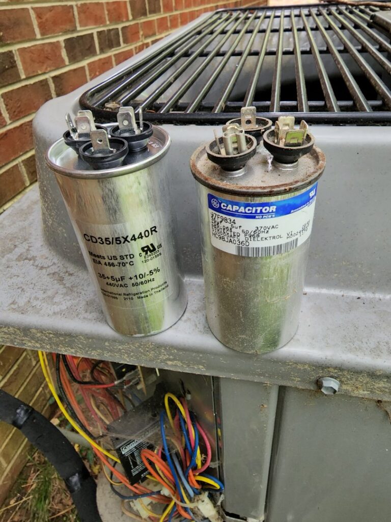Two HVAC capacitors placed on an outdoor AC unit, ready for replacement or repair by Sizemore Heating & Air, LLC in Chapel Hill, NC