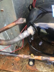 A close-up of a brazed copper line connection on an HVAC compressor, showing detailed work by Johnson's Heating and Cooling in Clarksville, TN.