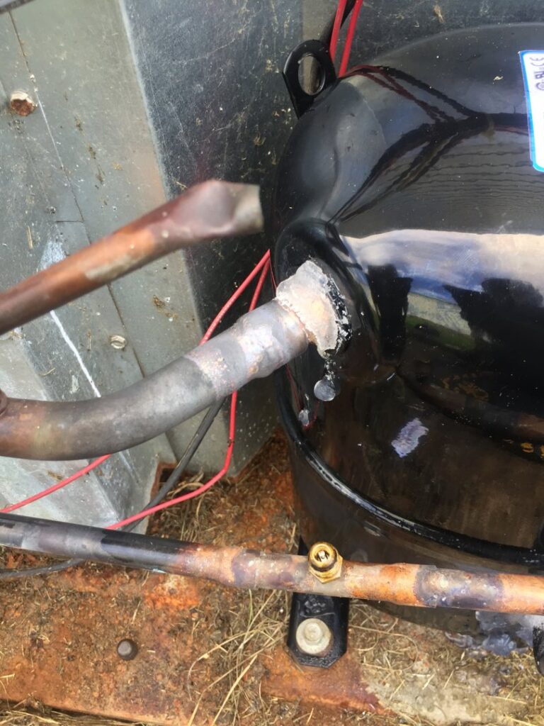 A close-up of a brazed copper line connection on an HVAC compressor, showing detailed work by Johnson's Heating and Cooling in Clarksville, TN.