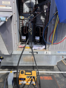 HVAC technicians performing compressor replacement and vacuuming lines with a pump for Mead Heating and Cooling in Kansas City, MO.