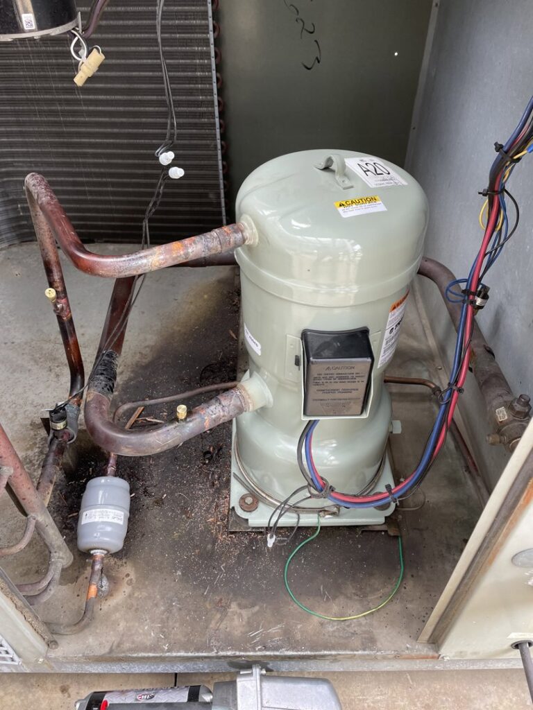 Close-up view of an HVAC compressor unit with wiring and piping, indicating inspection or service by Underwood Heating and Air Conditioning in Phenix City, AL