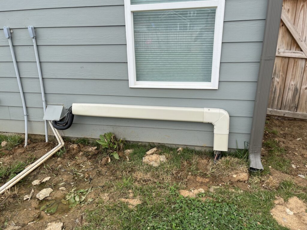 An exterior view of a house showing an HVAC condensate drain line cover installed by Rivertech Heating & Air Conditioning in Chattanooga, TN.