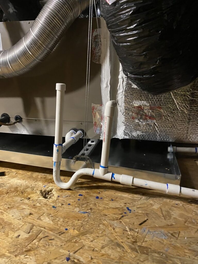 Newly installed PVC condensate drain lines for an indoor HVAC unit by Steadfast Mechanical in Gilbert, AZ.