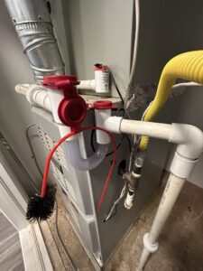 A close-up of an HVAC condensate trap and brush on an indoor unit, showing maintenance or installation by Bluestone Refrigeration LLC in Las Cruces, NM.
