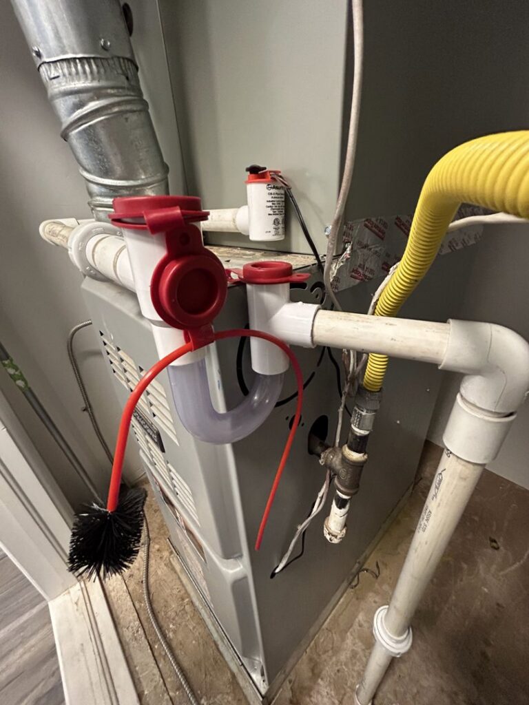 A close-up of an HVAC condensate trap and brush on an indoor unit, showing maintenance or installation by Bluestone Refrigeration LLC in Las Cruces, NM.