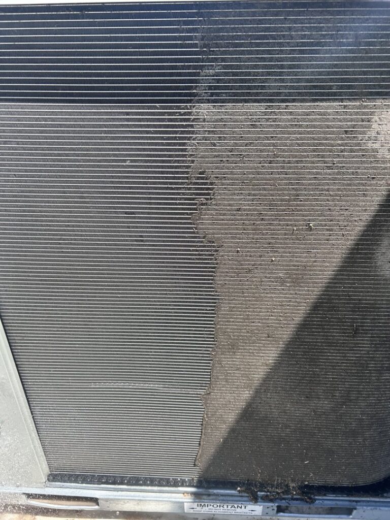 A close-up of an HVAC condenser coil, half cleaned and half dirty, demonstrating a cleaning service by KCC Mechanical, LLC in Sandy, UT.