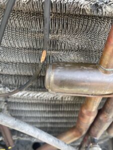 A close-up view of HVAC condenser coils and copper tubing, indicating detailed inspection or maintenance by DeltaCool in Jonesboro, AR.