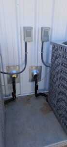Electrical conduits and refrigerant lines connected to outdoor HVAC condenser units by HoxAir Heating & Cooling in Phoenix, AZ