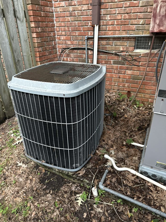 An outdoor HVAC condenser unit installed next to a brick house by Kirk Heating & Air Conditioning in Summerville, SC.