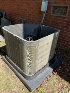 An outdoor HVAC condenser unit with its side panel removed, exposing coils for service by Mission HVAC in Huntsville, AL.