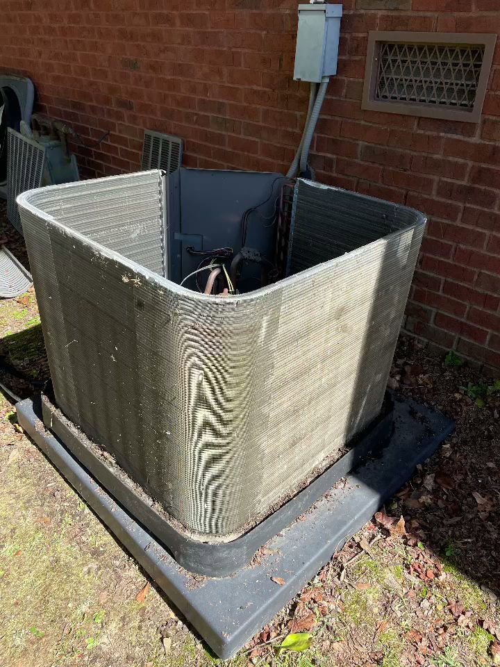 An outdoor HVAC condenser unit with its side panel removed, exposing coils for service by Mission HVAC in Huntsville, AL.
