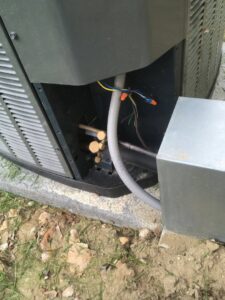 An outdoor HVAC condenser unit with exposed wiring and copper lines being serviced by Arrowhead Heating & Air Conditioning in Casper, WY.