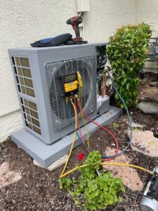 An outdoor HVAC condenser unit being serviced with gauges and hoses connected by Affordable Heating and Air in Chatsworth, CA.