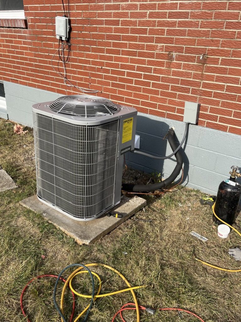 An outdoor HVAC condenser unit being serviced with gauges connected by GrinHouse HVACR in La Grange, KY.