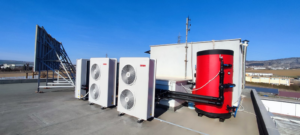 Rooftop installation of HVAC condenser units and a large red water tank by Κυριακιδης Στεφανος ''Team Gas'' in Évosmo, Greece