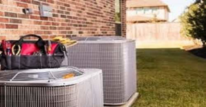 Two outdoor HVAC condenser units with a technician's toolbox, ready for service by Blanton & Son Heating and Cooling in Clayton, NC