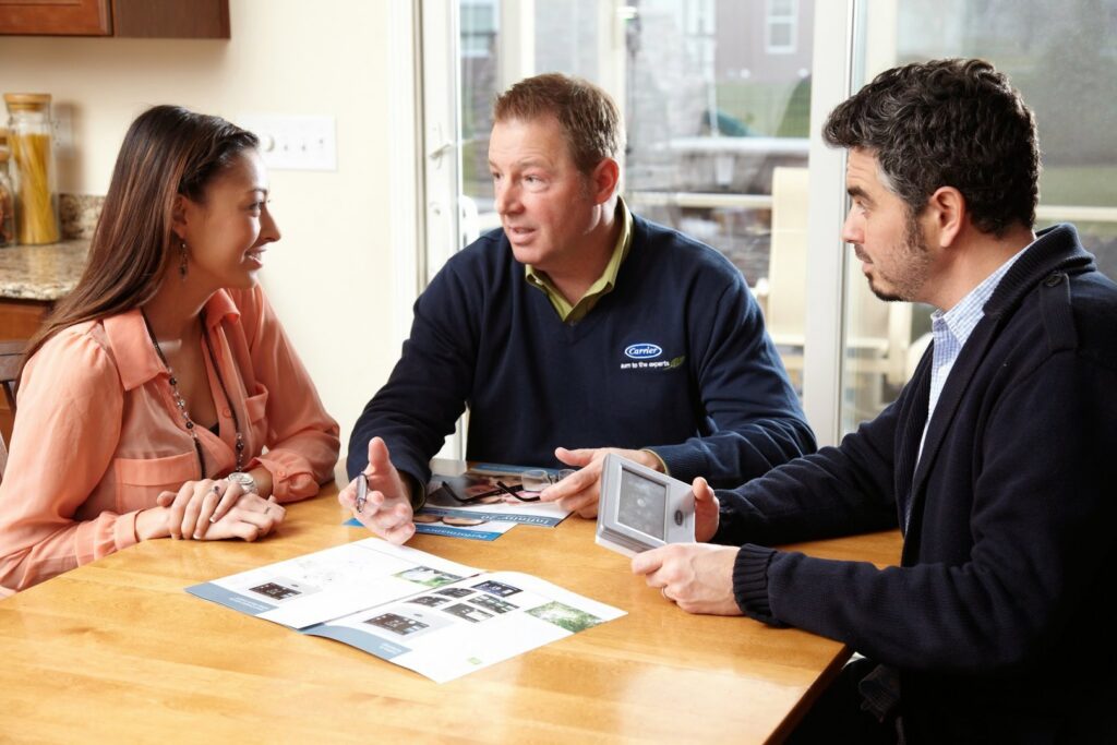 An HVAC technician from Bergmann Heating & Air Conditioning, LLC in Orem, UT, consulting with customers about heating and cooling solutions