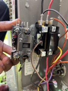 A technician holding an electrical contactor during an HVAC repair or replacement service by Keith HVAC & Electrical Enterprises LLC in New Orleans, LA.