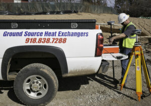 An HVAC contractor surveying a geothermal installation site from a service truck for Environmental Loop Service in Tulsa, OK.