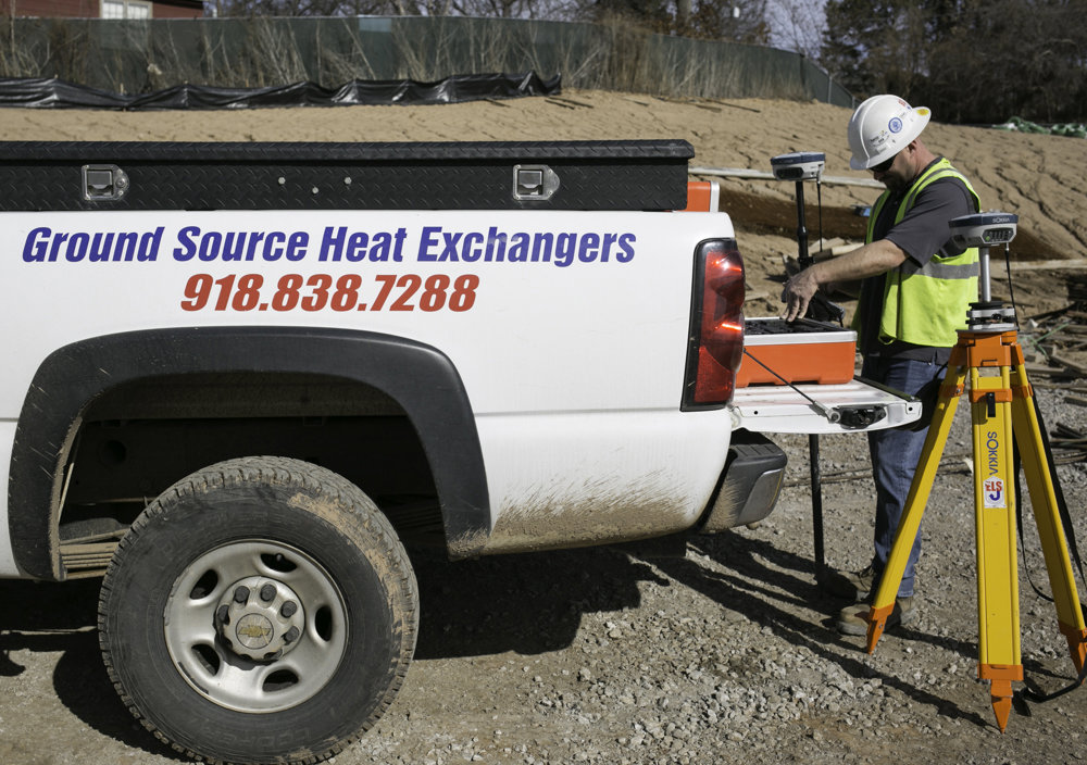 An HVAC contractor surveying a geothermal installation site from a service truck for Environmental Loop Service in Tulsa, OK.