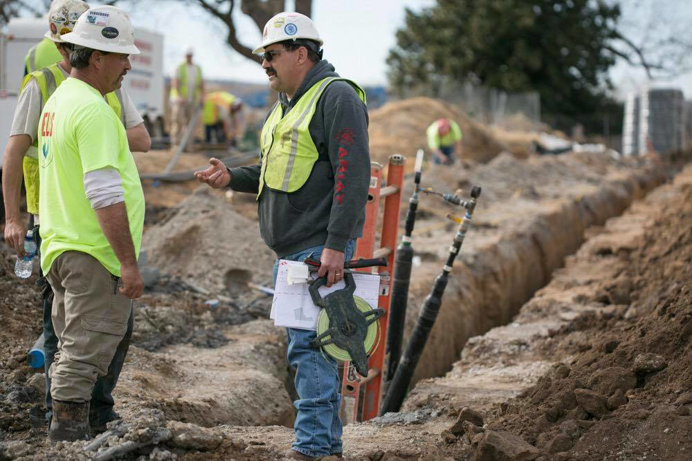 HVAC contractors installing ground source heat exchanger pipes in a trench for Environmental Loop Service in Tulsa, OK.