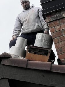 HVAC contractors from Five Star Chimney Repair working on a brick chimney and cap on a roof in Hillsboro, OR.