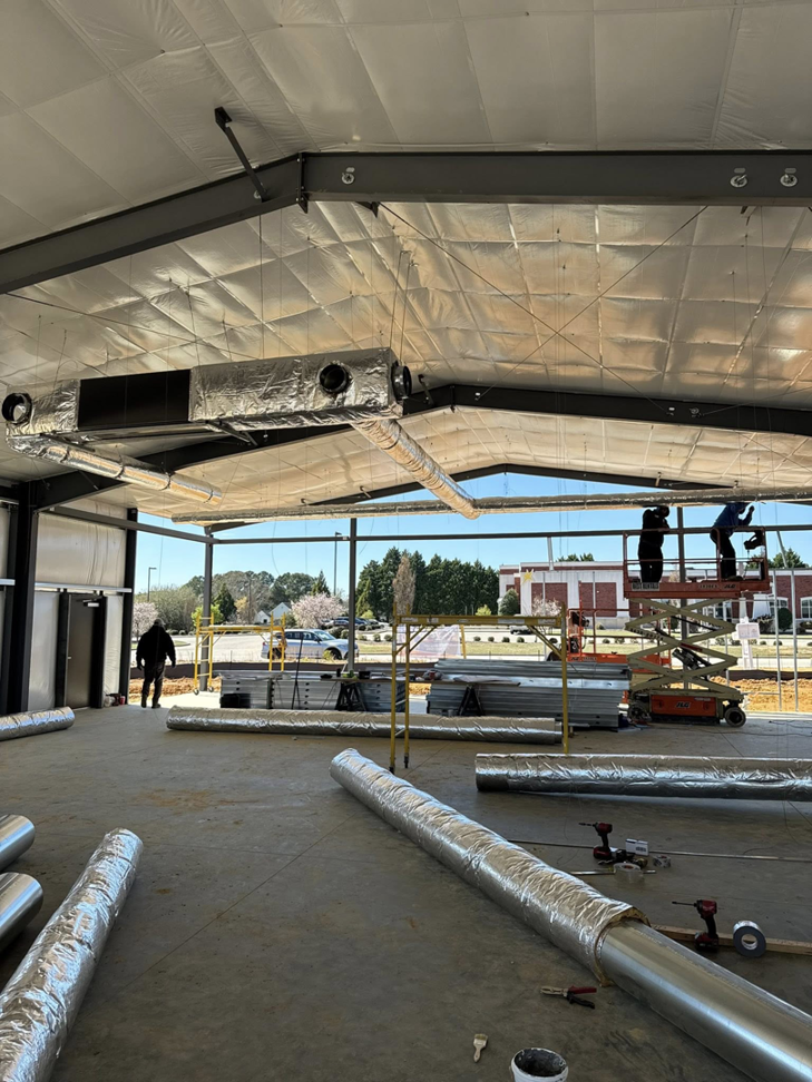 HVAC crew members installing large insulated ductwork using scissor lifts for Delta Heating, Cooling, Plumbing in Wilson, NC.