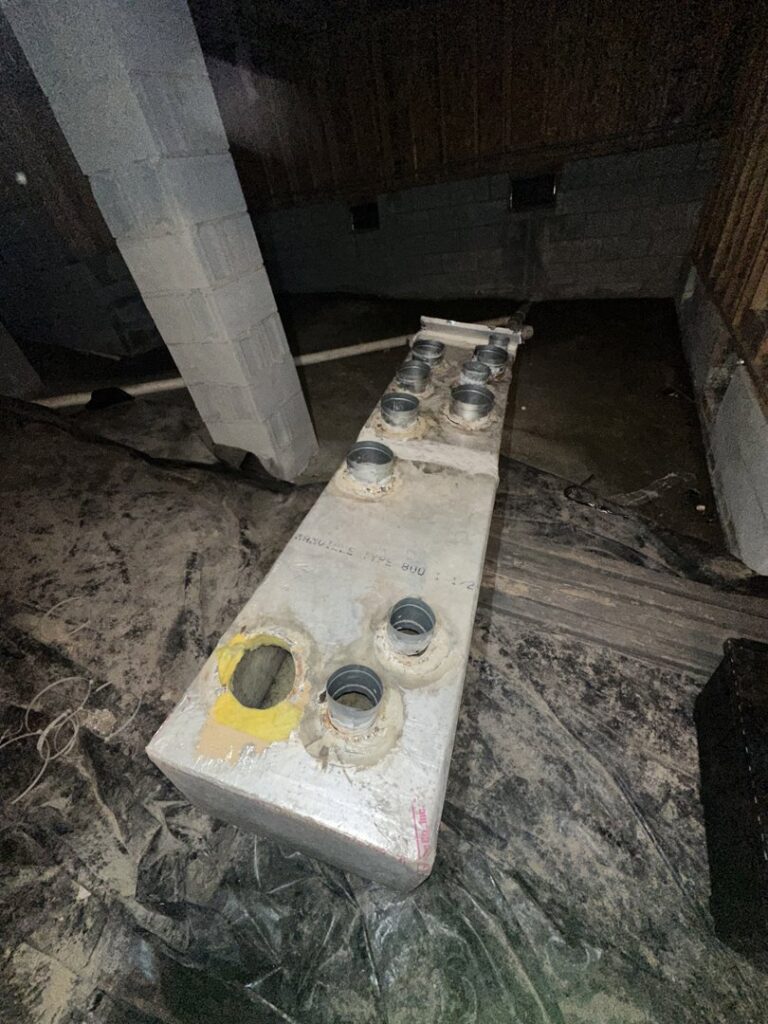 An HVAC duct distribution box with multiple openings installed in a crawl space by Arctic Desert Cooling & Heating in Concord, NC