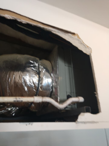 HVAC ductwork and an air handler unit visible through a wall opening by Ryans Ambient Air in Portsmouth, VA.