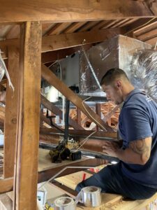 An Ultimate Air Conditioning technician installing or repairing ductwork and an air handler in an attic in Pearl City, HI