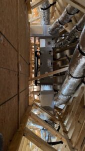 HVAC ductwork and an air handler unit installed in the unfinished attic of a new construction home by Heads Heating & Air Conditioning in Theodore, AL.