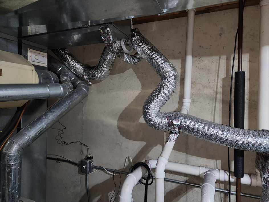 Complex HVAC ductwork and furnace connections in a utility room, demonstrating services by Pro Power Air Duct & Dryer Vent Cleaning in Kenosha, WI.