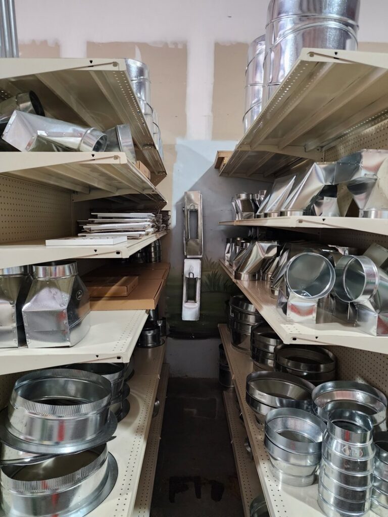 Shelves stocked with various metal ductwork components and fittings at Aire Care Mechanical's facility in Knoxville, TN.