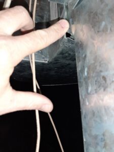 A hand pointing to a connection point in metal HVAC ductwork, showing installation detail by Arrowseal of Billings HVAC in Billings, MT.