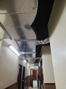Exposed metal HVAC ductwork running along an office hallway ceiling, installed by Jons-Air in Carmel, IN.