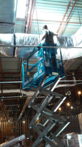A technician installing new HVAC ductwork in a commercial building for Avallone Mechanical Company in Las Cruces, NM.