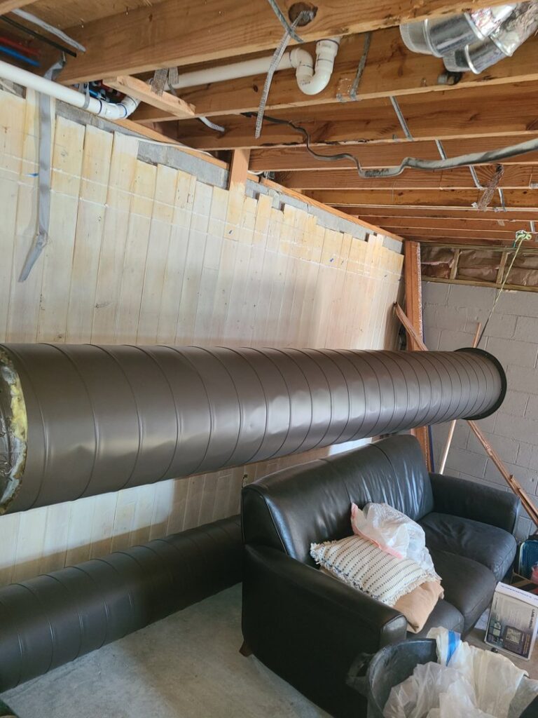 Large brown HVAC ductwork being installed in a basement or crawl space by Rivertech Heating & Air Conditioning in Chattanooga, TN.